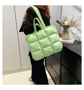 Scatto lifestyle di una grande borsa tote trapuntata verde chiaro con manici imbottiti