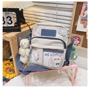 Détail du sac bandoulière en toile avec poche transparente, carte lapin et ours peluche