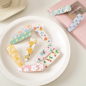 Set of 9 cute acrylic flower and strawberry hair clips on a white ceramic plate