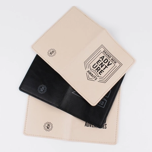Detail of printed PU leather passport holders in beige and black with adventure text