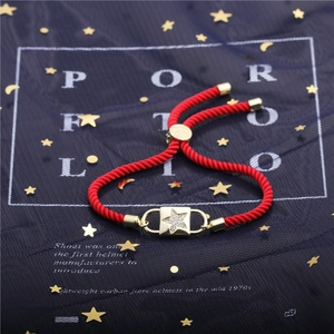 Adjustable red cord bracelet featuring a gold star charm with sparkling zircons