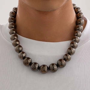 Close-up of chunky dark grey glossy bead necklace worn by male model on white t-shirt