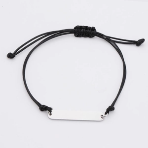Macro shot of silver-tone stainless steel bar on black woven bracelet with smooth finish