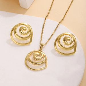 Close-up of golden spiral jewelry set featuring circular earrings and necklace on white podium