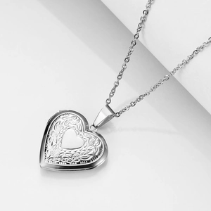 Macro view of silver heart locket pendant with floral engraving and polished finish