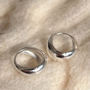 Polished 925 sterling silver hoop earrings on soft beige fabric background