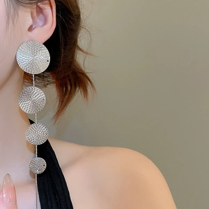 Detail of silver drop earrings featuring four graduated textured metal discs on model