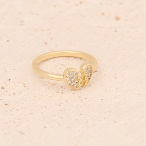 Detail of a broken heart gold ring with sparkling cubic zirconia on a textured surface