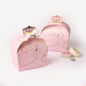Scatola regalo rosa a forma di corona con dettagli dorati, fiocco bianco e cuore d'argento