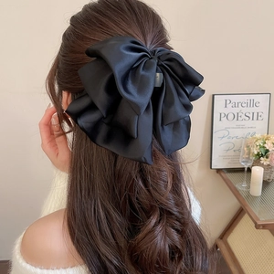 Detailed back view of a large black satin bow hair claw clip with multi-layered fabric