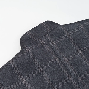 Dettaglio del tessuto scozzese di alta qualità e del bavero strutturato su questo blazer