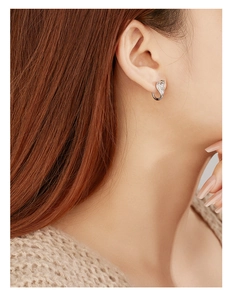 Close-up of S925 silver cobra hoop earrings with sparkling white zircons on a model