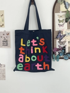 Detail of colorful towel embroidery letter design on deep blue canvas tote bag