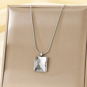 Macro detail of clear rectangular crystal pendant on silver snake chain jewelry