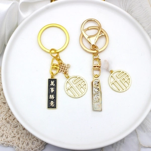Golden DIY keychain set with Fu and Wanshi Shengyi tags on a minimalist white plate