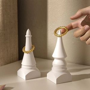 Geometric gold rings with beaded and faceted textures on white cone jewelry stands
