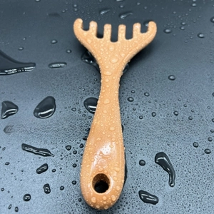 Macro detail of brown antler-shaped scalp massager with four blunt teeth on wet surface