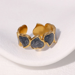 Macro detail of gold-plated open heart ring with grey marble inlay on a white plate