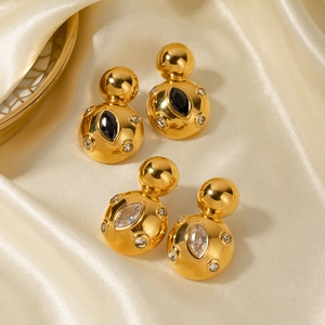 Macro detail of 18k gold earrings with marquise black and clear stones on satin