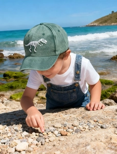 Detailed close-up of a green kids baseball cap with dinosaur skeleton embroidery