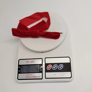 Weight measurement of a red velvet Christmas bow decoration on a white digital scale