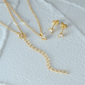 Detail of S925 silver heart necklace and earrings set with zircons on stone surface