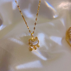 Close-up of a gold Ruyi lock necklace with white jade inlay and small bells on silk