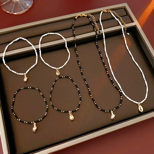 Detail view of a shell jewelry set with black and white beads and gold pendants