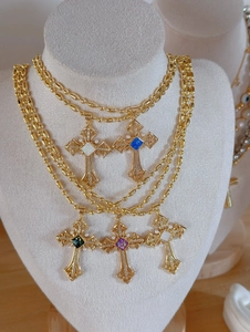 Detailed layered display of vintage gold cross necklaces with colorful gemstones