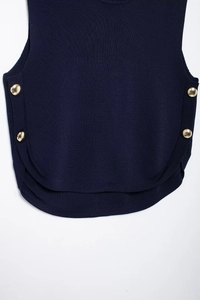 Detail view of navy knit vest with golden side buttons and elegant curved hemline