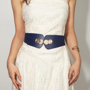 Close-up of a wide navy blue elastic waist belt with a gold double-ring metal buckle on a dress
