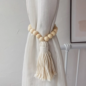 Minimalist wooden bead curtain tieback with cotton tassels on a white sheer curtain