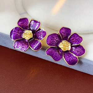 Vista macro de pendientes de flores de esmalte morado con bordes y centro dorados