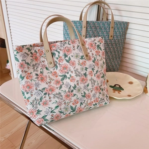 Detail of pink and cyan floral tote bags with synthetic leather handles and metal rivets