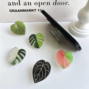 Five leaf and heart shaped acrylic phone grips shown on white background and black phone