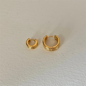 Macro view of gold striped 925 sterling silver hoop earrings with a textured surface
