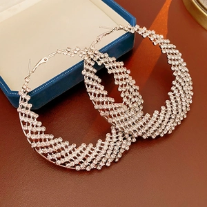 Detailed view of silver hoop earrings with dense rhinestone pavé on blue jewelry box