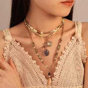 Detail of layered bohemian necklace with wooden beads and vintage coin charms