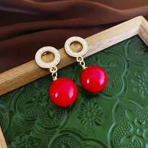 Close-up of vintage geometric earrings with red ceramic beads and small white pearls