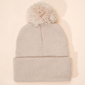 Detailed knit texture of beige winter beanie featuring a soft fluffy pom-pom top