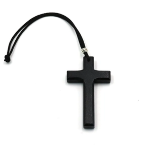 Detail eines mattschwarzen Holzkreuz-Anhängers mit geflochtener Kordel und Metallring