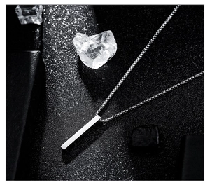 Macro view of a minimalist silver rectangular bar pendant on a box chain for couples