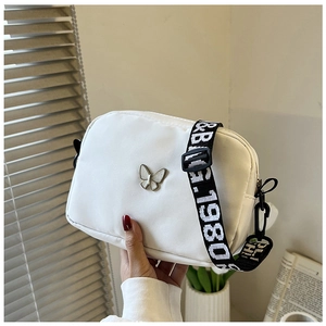 Detail of white nylon crossbody bag with silver butterfly and wide 1980& letter strap