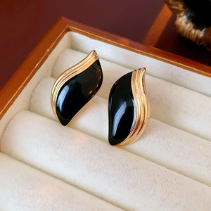 Gros plan sur les boucles d'oreilles vintage en émail noir avec bordure dorée en boîte