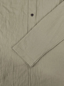 Macro detail of khaki linen shirt fabric featuring a black button and fine stitching texture