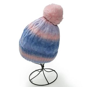 Pink and blue gradient knit beanie with a faux fur pompom on a display stand