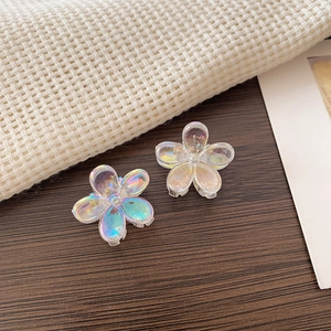 Close-up of iridescent mini flower hair claws with aurora coating on plaid background