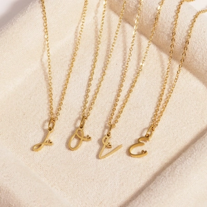 Close-up of four gold stainless steel chains with LOVE letter pendants on beige velvet