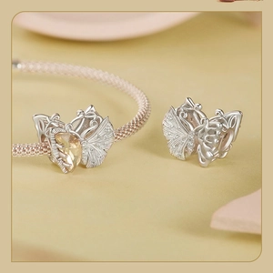 Macro view of butterfly charm with yellow gemstone and cubic zirconia on woven bracelet