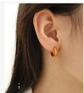 Detailed close-up of gold-plated textured hoop earrings with industrial ribbed finish